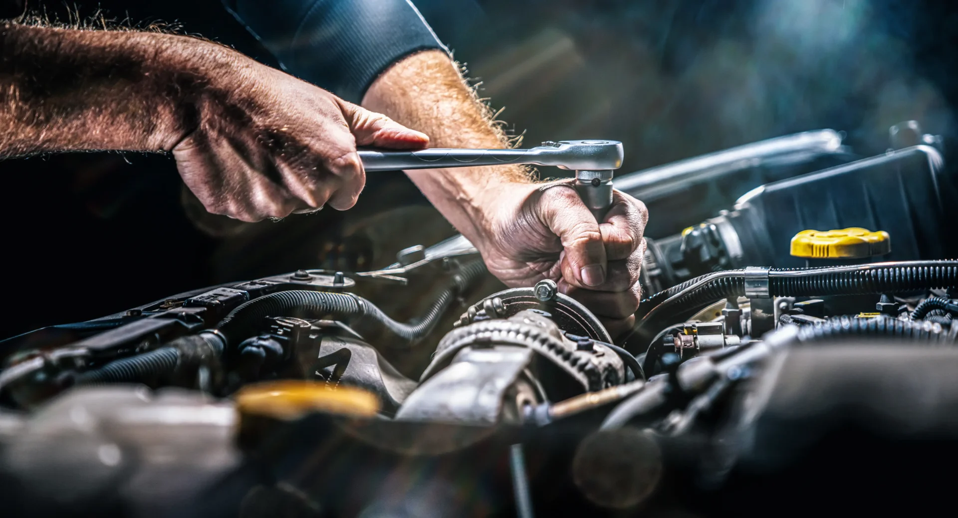 Mechanic using ratchet on car engine.