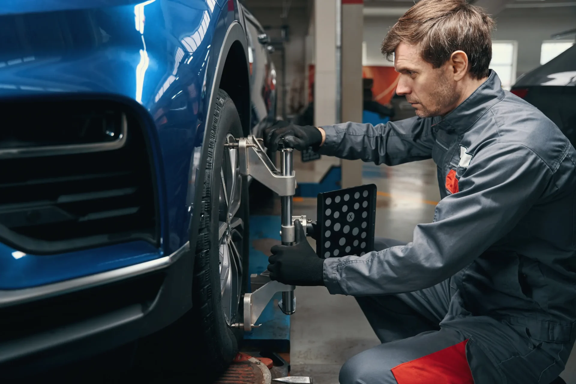 Mechanic aligning blue car wheel.