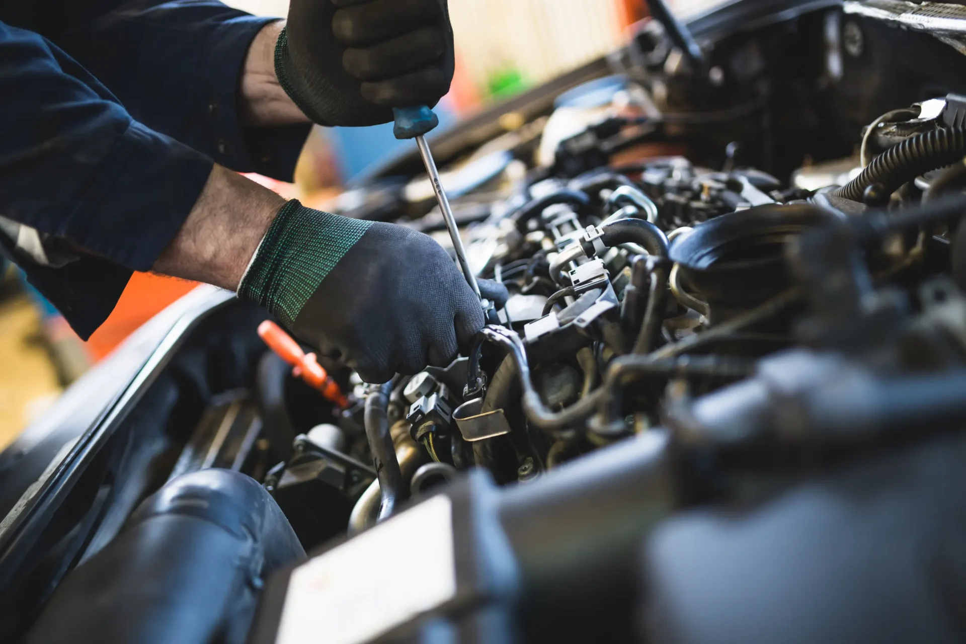 Mechanic repairing car engine with screwdriver.